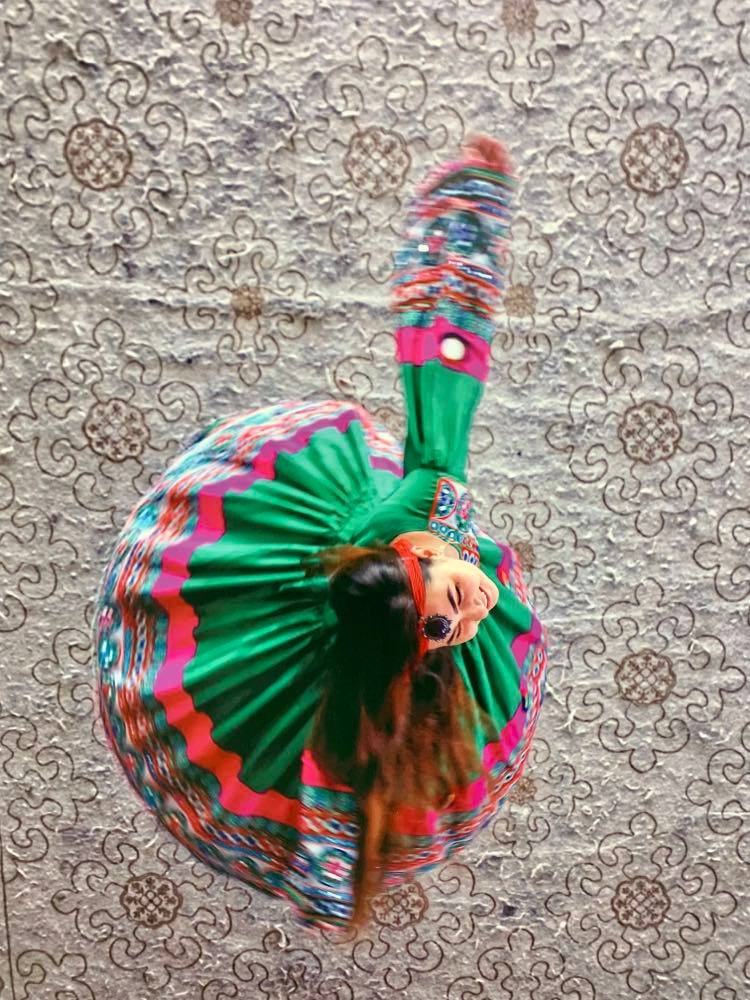 Una ragazza con un abito molto colorato vista dall'alto mentre balla girando su se stessa